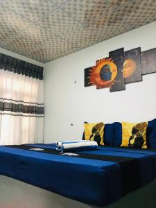 a room with a bed with blue sheets and a painting on the wall at Priya Homestay Kandalama in Dambulla