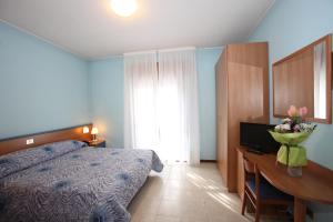 1 dormitorio con 1 cama y escritorio con TV en Albergo Ridente, en Lido di Jesolo