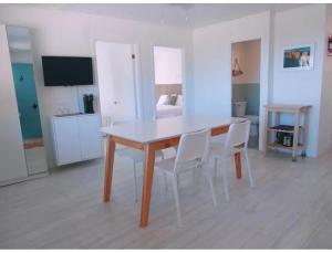 a dining room with a white table and white chairs at En Route Vers l'Infini in Perce