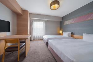 a hotel room with two beds and a desk at Hotel Resol Trinity Hakata in Fukuoka