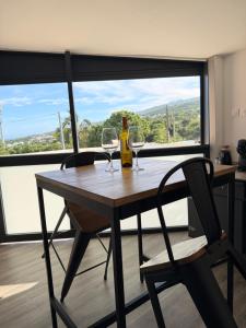 a table with two wine glasses and a bottle at ATÈRLA - Appartement de charme et SPA privée in La Possession +20 photos