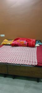a bed with a red and white comforter on it at Meena Sadan in Prayagraj