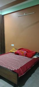 a bed with a red comforter in a room at Meena Sadan in Prayagraj
