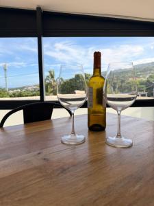 a bottle of wine and two wine glasses on a table at ATÈRLA - Appartement de charme et SPA privée in La Possession