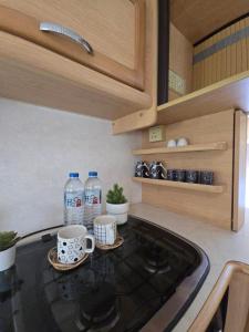 a kitchen with two cups and water bottles on the counter at TheBoxCaravan in Ban Pak Ram
