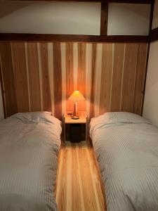 a bedroom with two beds and a table with a lamp at ゲストハウス山音 in Takayama