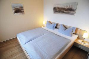 a bedroom with a large bed with two lamps on it at Haus "Zur Düne" in Norddorf
