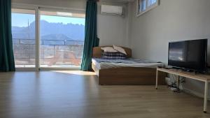 a room with a bed and a television and a desk at Gilson Guesthouse in Sokcho