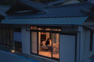 a woman sitting in a chair in a window at The Nature Uno 2026年リノベーション 直島好アクセス 古民家一棟貸切 最大4名2ldk平家 クイーンベッド2台 in Tamano +53 photos