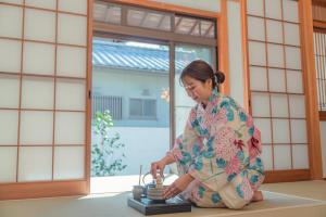 a woman in a kimono sitting on the floor at The Nature Uno 2026年リノベーション 直島好アクセス 古民家一棟貸切 最大4名2ldk平家 クイーンベッド2台 in Tamano