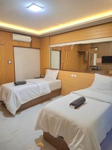 a hotel room with two beds and a projection screen at 7 Day Inn in Gili Trawangan