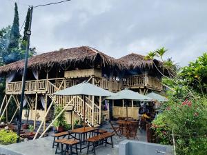 a restaurant with tables and umbrellas in front of a building at D Royale Tapos Resort Bogor in Tapos