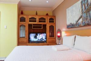 a bedroom with a bed and a tv in a cabinet at Mamli Guestlodge & Conferencing in Schoemansdal