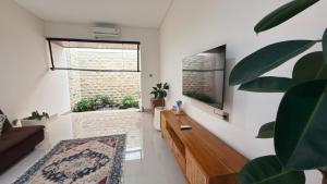 a living room with a large window and a tv at Emstaliese & Palmarosa Villas Seminyak in Legian