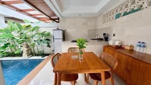 a kitchen with a wooden table and some plants at Emstaliese & Palmarosa Villas Seminyak in Legian