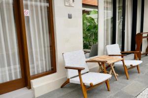 two chairs and a wooden table on a patio at Emstaliese & Palmarosa Villas Seminyak in Legian
