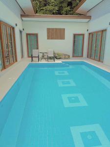 a large blue swimming pool with two chairs and a table at Chaisona at Khanom Cottage in Ban Phaeng
