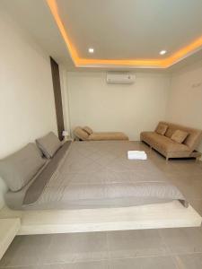 a bedroom with a large bed and a couch at Chaisona at Khanom Cottage in Ban Phaeng +4 photos