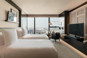 a hotel room with two beds and a flat screen tv at Rosewood Phnom Penh in Phnom Penh
