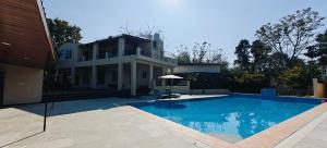 a house with a swimming pool in front of a house at The Jungle Gate Villa in Udaipur