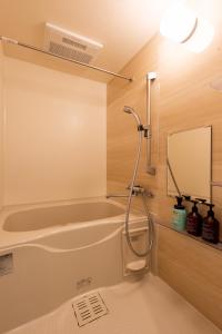 a shower in a bathroom with a tub and a mirror at Nagomi Apartment Hotel in Hatsukaichi
