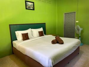 a teddy bear laying on a bed in a green room at ABC Bungalow in Ban Tai