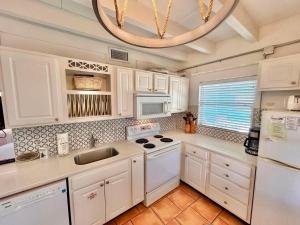 a kitchen with white cabinets and a white stove top oven at Baked Beach Bungalow in St. George Island