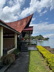 a building with a red roof next to the water at Romlan Guesthouse in Tuktuk Siadong