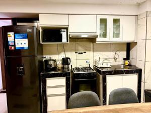 a kitchen with a black refrigerator and white cabinets at Comfort House in Lima