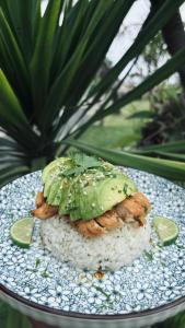 a plate with a chicken and rice and a plant at Trika Surfcamp Bali in Airsatang