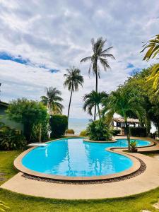 a large swimming pool with palm trees and the ocean at Phangan Beach Resort in Ban Tai