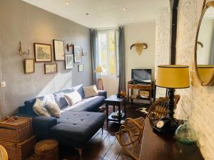 a living room with a blue couch and a tv at charming guest house in Bolbec