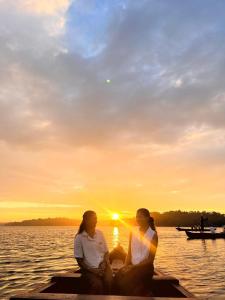 two women sitting on a dock watching the sunset at Karma Homestay in Munroe Island
