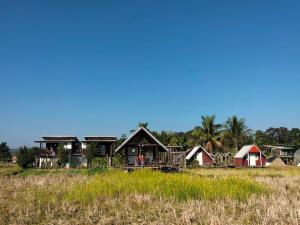 a group of houses in a field with trees at Ricefield Homestay มองนาภูคาน่านโฮมสเตย์ in Ban Thon (1)