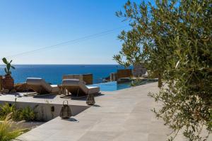 a patio with chairs and the ocean in the background at Villa Noema in Agiassos