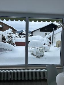 a window with a view of a yard covered in snow at Staufen Auszeit in Oberstaufen