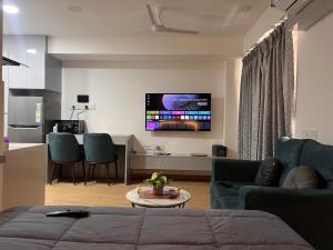 a living room with a couch and a table and a kitchen at NEON - Nirvana Stays With PVT Balcony -1 Km from Airport in Pune