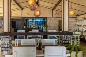 a restaurant with a bar with white chairs and lights at Phangan Beach Resort in Ban Tai