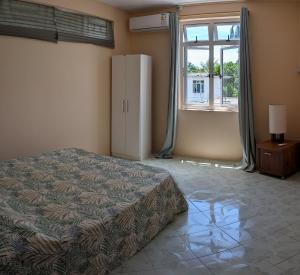 a bedroom with a bed and a large window at Desirella Villa APARTMENT in Mahébourg +7 photos