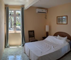 a bedroom with a white bed and a window at Desirella Villa APARTMENT in Mahébourg