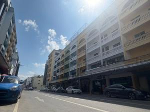 a street with cars parked in front of buildings at Hometown Stays Hatyai in Hat Yai
