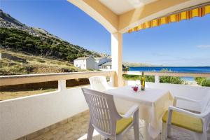 a white table and chairs on a balcony with the ocean at Sladana direct at the beach in Metajna +77 photos