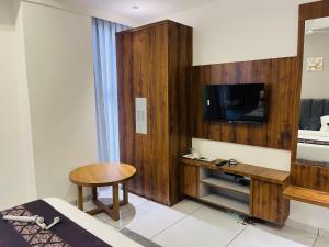 a hotel room with a bed and a tv and a table at Hotel Royal Empire in Gandhinagar