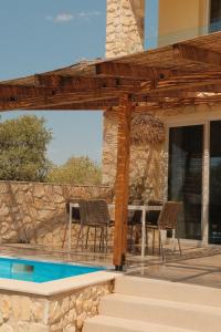a pergola with chairs and a table next to a pool at IVANKA'S VILLAS in Skala Rachoniou