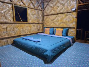 a large bed in a room with a wooden wall at Kohmook Money RUEAN PHAI in Trang