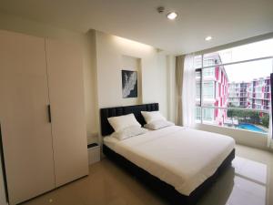 a bedroom with a white bed and a window at Pattaya Pool View Condo in Nong Prue