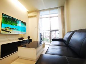 a living room with a black leather couch and a flat screen tv at Pattaya Pool View Condo in Nong Prue