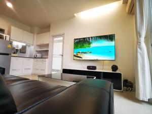 a living room with a couch and a tv on the wall at Pattaya Pool View Condo in Nong Prue