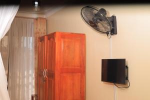a room with a wooden cabinet and a fan on the wall at HOIMA KOLPING HOTEL in Hoima