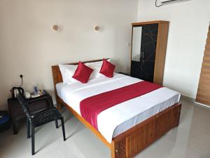 a bedroom with a bed with red pillows and a chair at Lake Star Beach Resort in Kappil